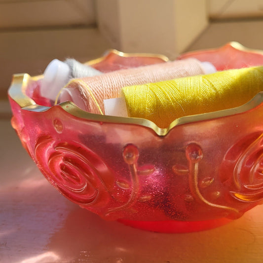 Decorative bowl, pink edged in gold. Displayed holding cotton reels.