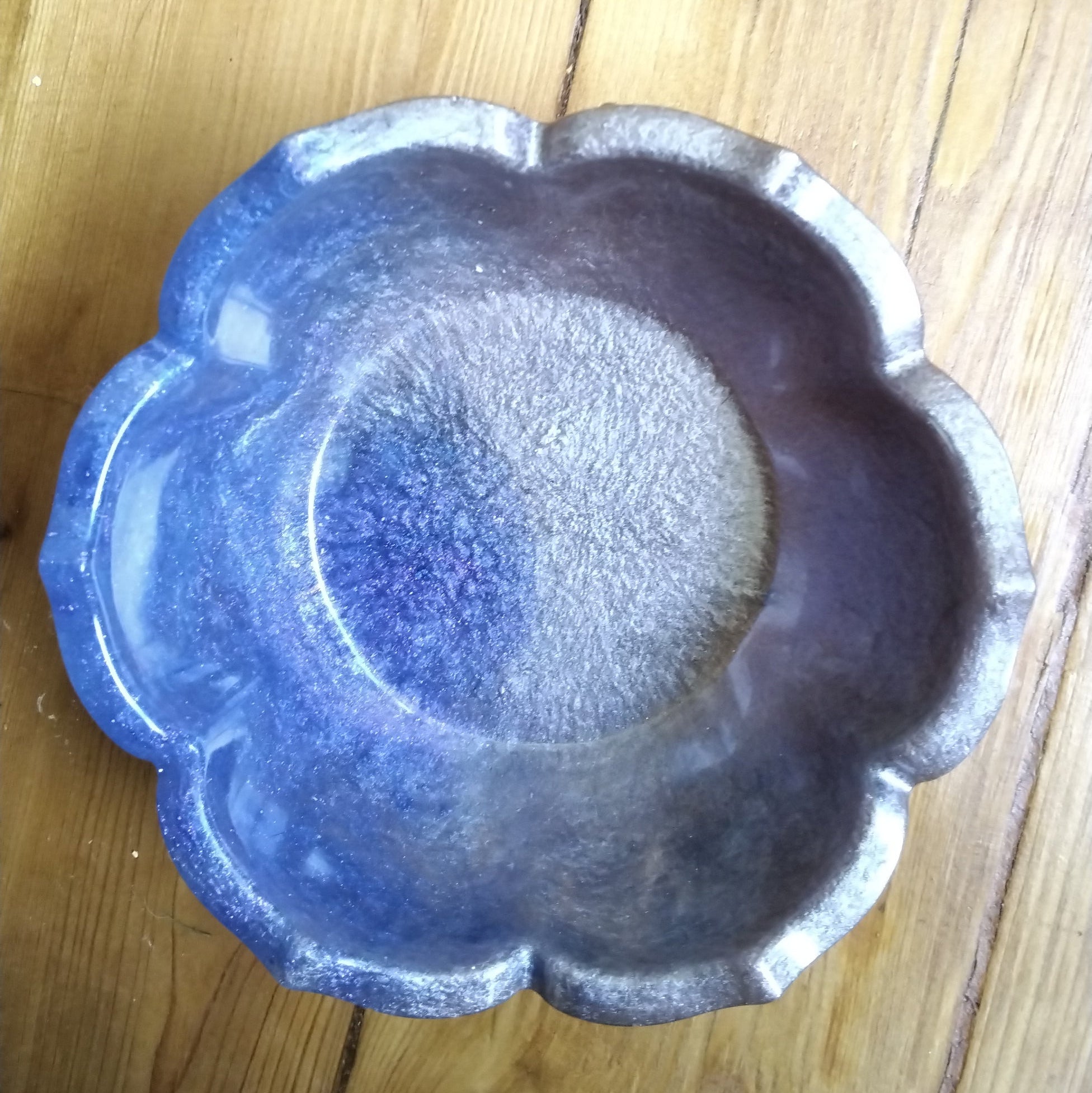 Decorative blue and silver flower-shaped  resin bowl , top down view on a wooden background.