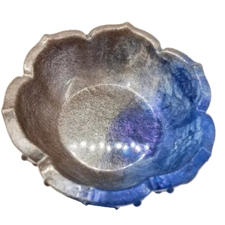 Looking down on decorative blue and silver flower-shaped  resin bowl on a plain white background.