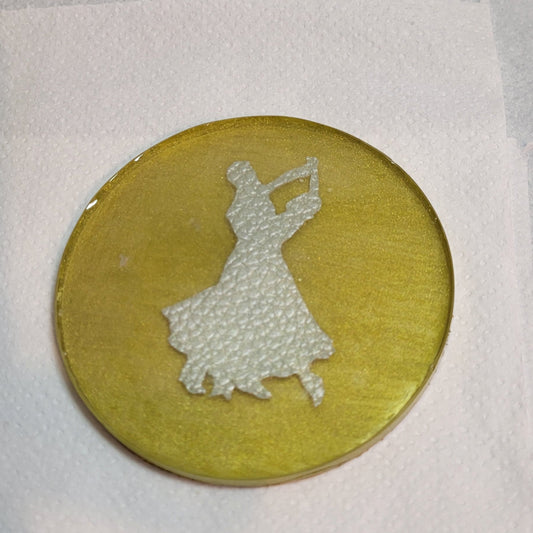Gold coloured resin circular drinks coaster. Inside is a faux leather pair of ballroom dancers.