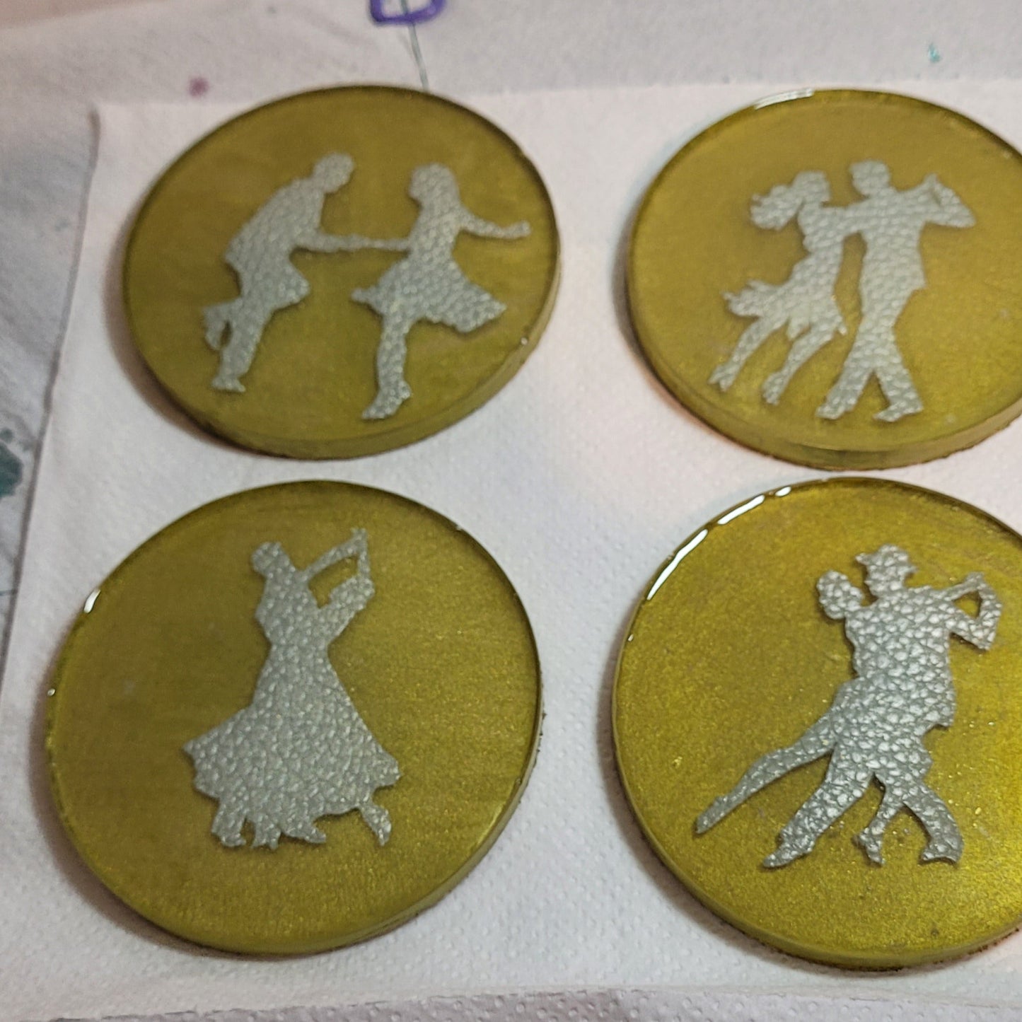 Gold coloured resin circular drinks coaster. Inside, each has a faux leather pair of dancers.