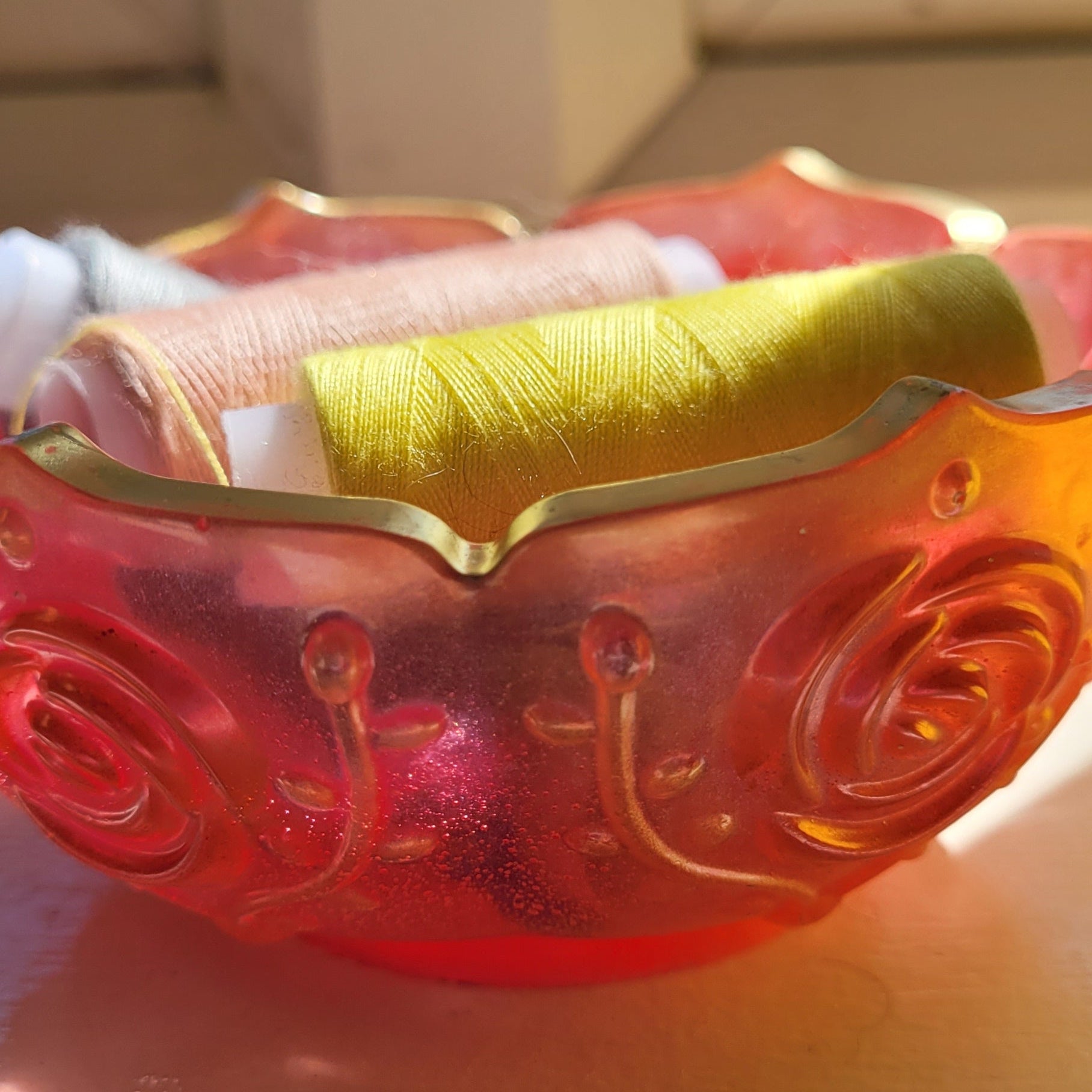 Decorative bowl, pink edged in gold. Displayed holding cotton reels.