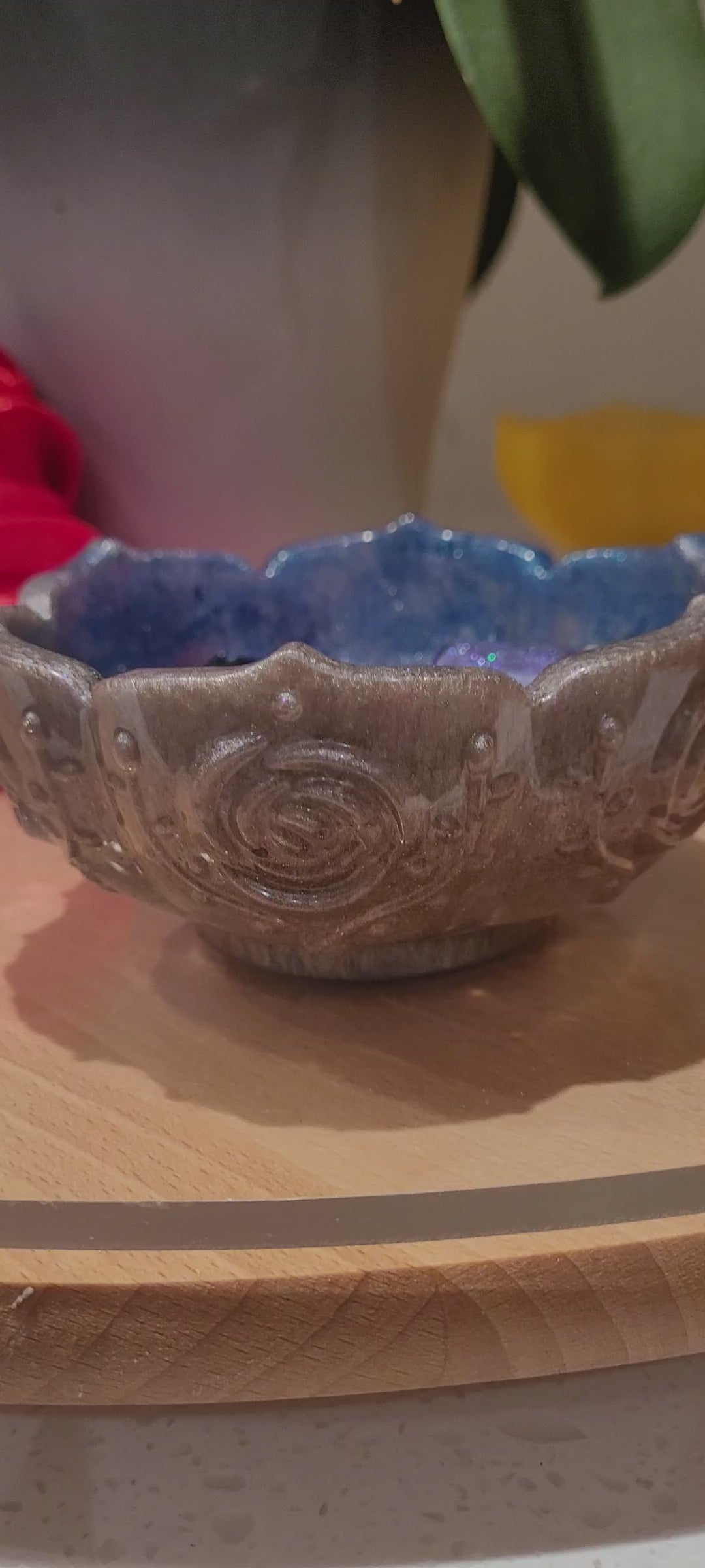 Decorative blue and silver flower-shaped  resin bowl on a wooden table.